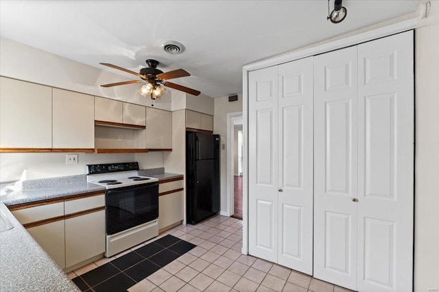 kitchen with visible vents, range with electric cooktop, freestanding refrigerator, light countertops, and light tile patterned flooring