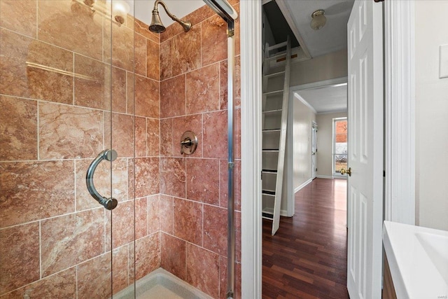 bathroom with a stall shower, wood finished floors, and baseboards