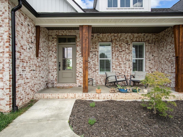 entrance to property with a porch, brick siding, and board and batten siding