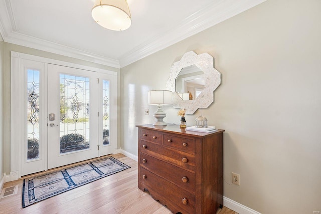 entrance foyer with visible vents, baseboards, crown molding, and light wood-style floors