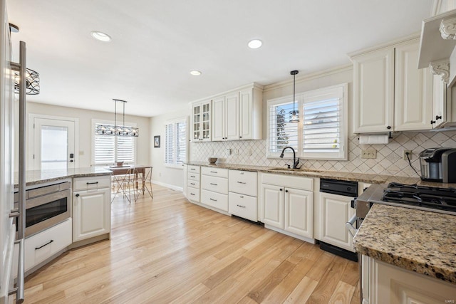 kitchen featuring a sink, light wood-type flooring, tasteful backsplash, and decorative light fixtures