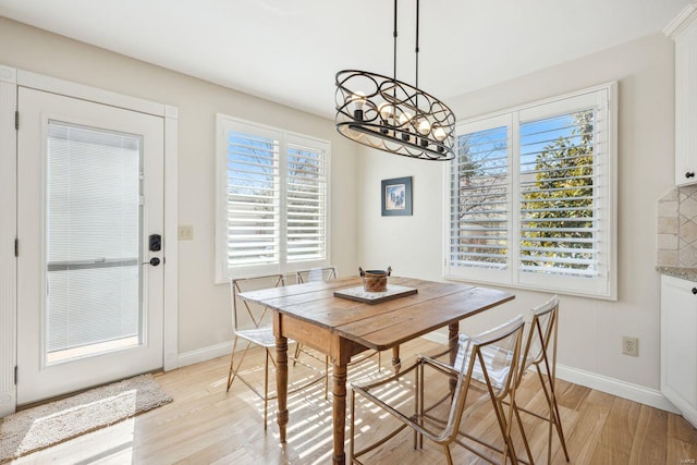 dining area with light wood-style flooring, baseboards, and a chandelier