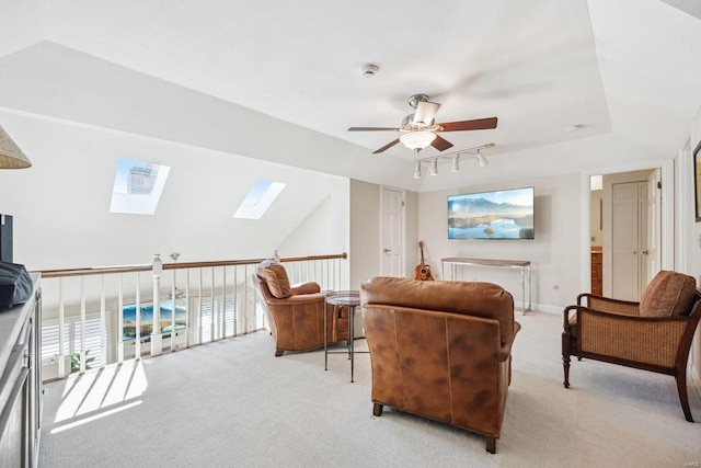 living room with baseboards, ceiling fan, rail lighting, light carpet, and lofted ceiling with skylight