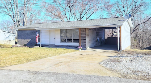 ranch-style house with a carport, roof with shingles, concrete driveway, a front yard, and brick siding