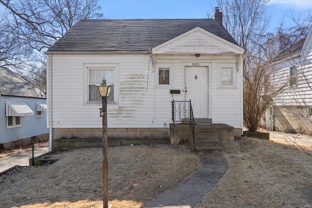 view of front of house with a shingled roof and a chimney