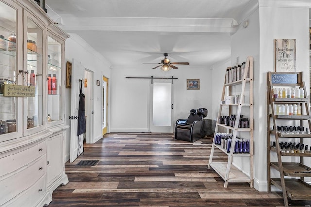 living area with a barn door, dark wood-type flooring, a ceiling fan, baseboards, and crown molding