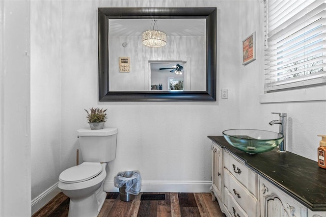 half bathroom with baseboards, toilet, ceiling fan, wood finished floors, and vanity