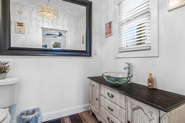 half bath featuring baseboards, a ceiling fan, toilet, wood finished floors, and vanity