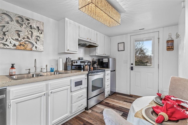 kitchen featuring under cabinet range hood, dark wood-type flooring, a sink, white cabinetry, and appliances with stainless steel finishes