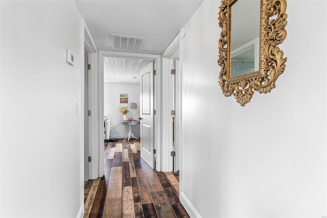 hall with dark wood-style flooring, visible vents, and baseboards