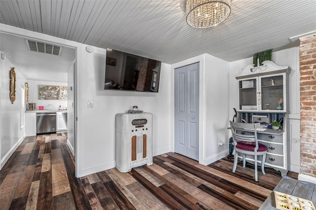 corridor featuring hardwood / wood-style flooring, baseboards, brick wall, and visible vents