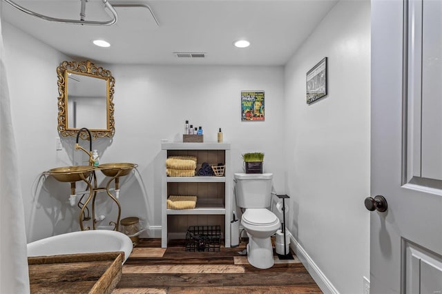 bathroom with toilet, wood finished floors, visible vents, and baseboards