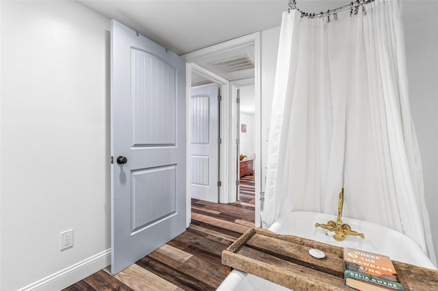 hall featuring dark wood-style floors, visible vents, and baseboards