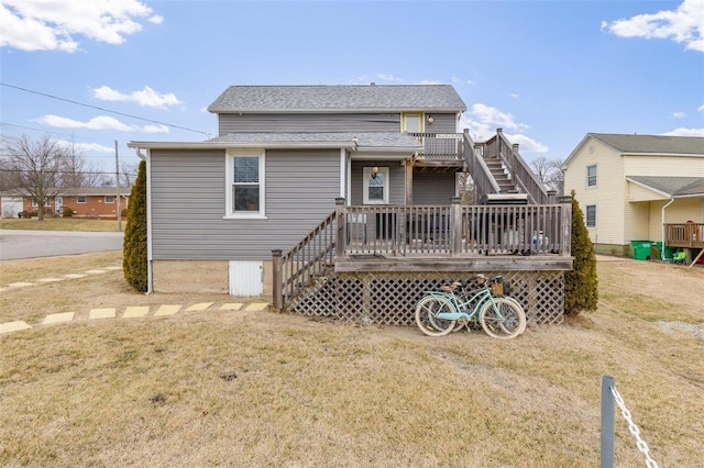 rear view of house featuring roof with shingles, a lawn, a wooden deck, and stairs