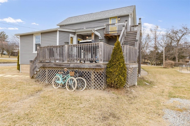 back of house featuring a shingled roof, stairway, a deck, and a yard