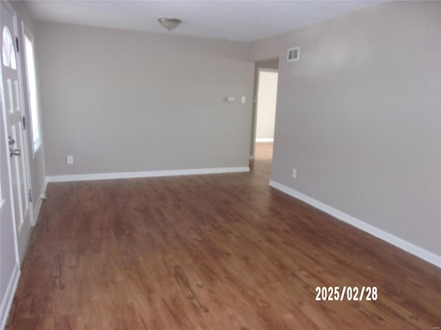 spare room with visible vents, baseboards, and wood finished floors