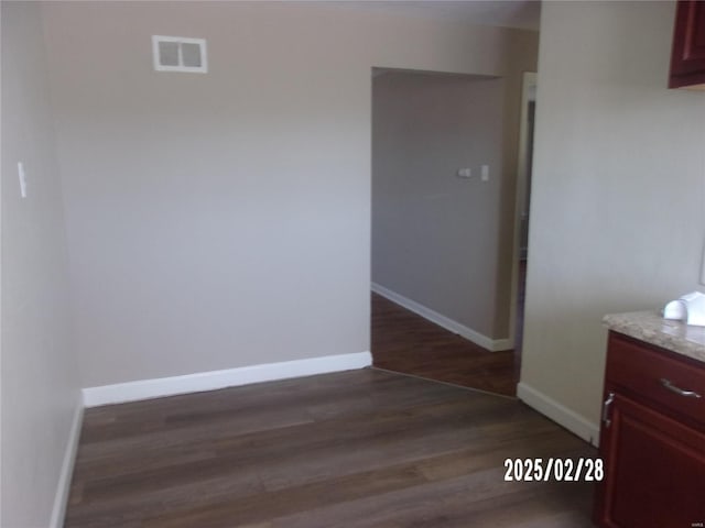 interior space with visible vents, baseboards, and dark wood-type flooring