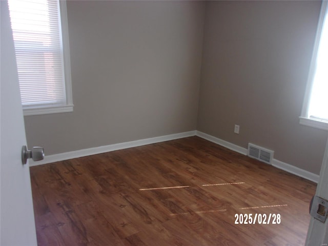 unfurnished room with visible vents, baseboards, and wood finished floors