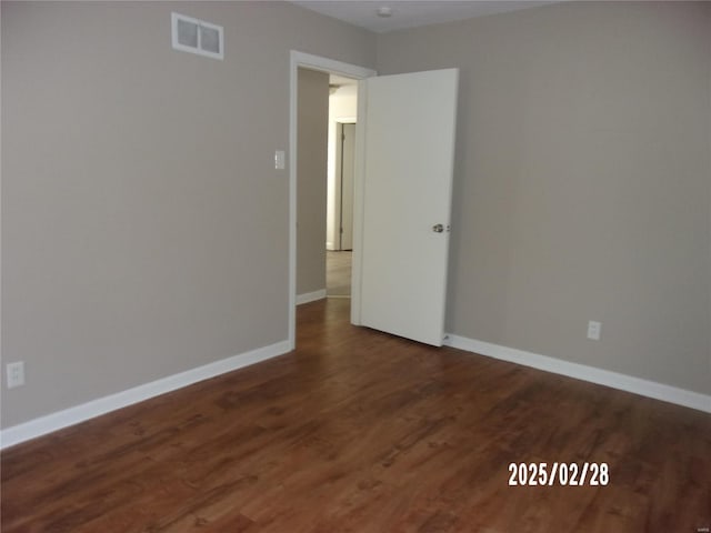 unfurnished room featuring dark wood-type flooring, baseboards, and visible vents