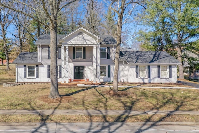 neoclassical / greek revival house with a front yard and brick siding