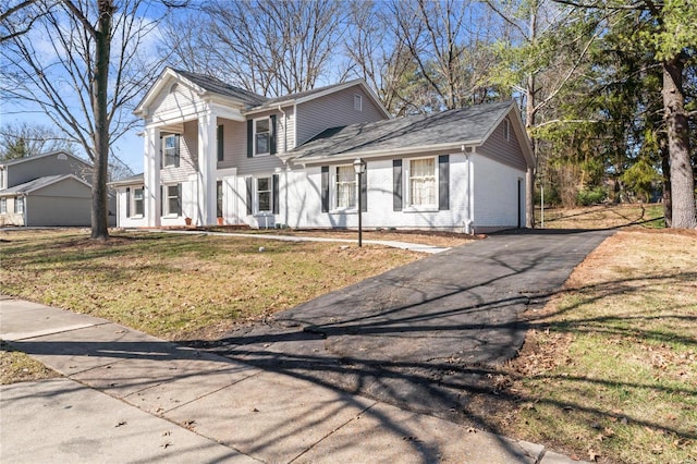 neoclassical home featuring brick siding, aphalt driveway, and a front yard