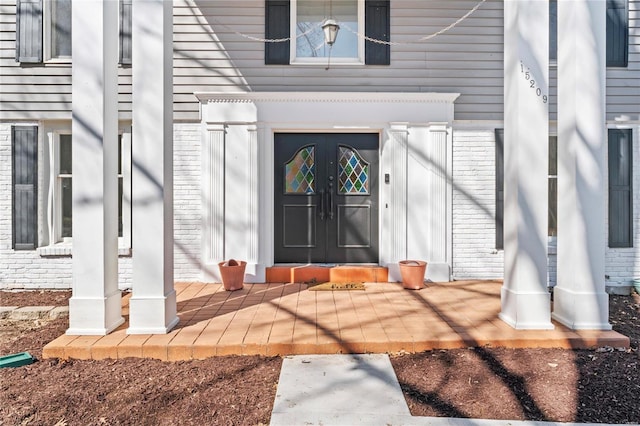 view of exterior entry featuring french doors and brick siding