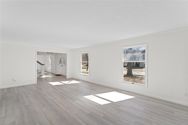 unfurnished living room with a textured ceiling, baseboards, ornamental molding, stairway, and light wood finished floors