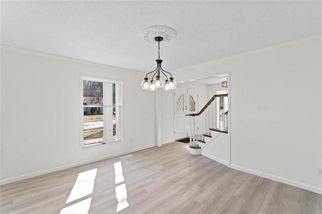 unfurnished dining area featuring light wood-type flooring, stairway, baseboards, and an inviting chandelier