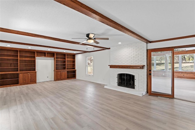 unfurnished living room with baseboards, beamed ceiling, a textured ceiling, light wood-type flooring, and a brick fireplace