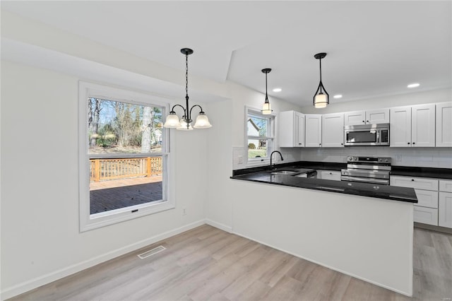 kitchen featuring tasteful backsplash, visible vents, dark countertops, appliances with stainless steel finishes, and a sink