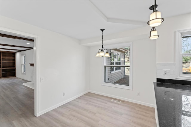 unfurnished dining area with light wood finished floors, beamed ceiling, visible vents, and baseboards