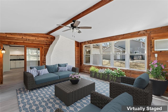 living area with vaulted ceiling with beams, wood finished floors, a ceiling fan, and wooden walls