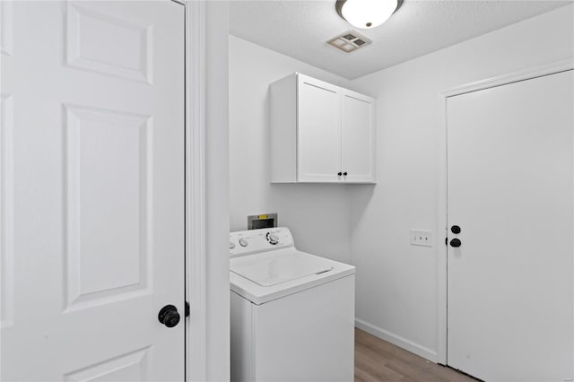 washroom featuring washer / dryer, cabinet space, visible vents, a textured ceiling, and light wood-type flooring