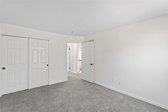 unfurnished bedroom featuring baseboards, visible vents, carpet, a textured ceiling, and a closet