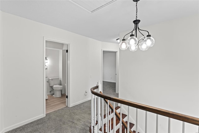 hallway featuring a chandelier, carpet, an upstairs landing, and baseboards