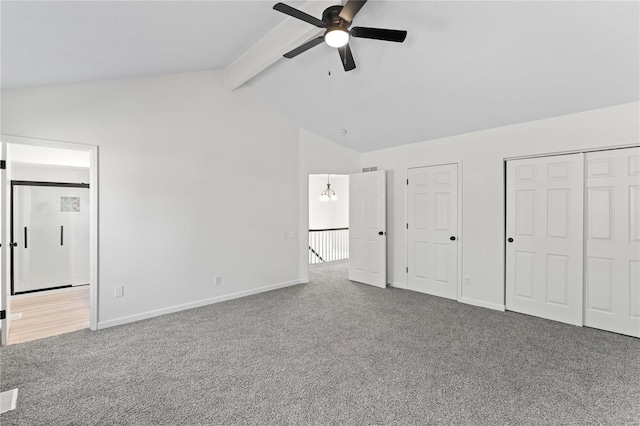 unfurnished bedroom featuring lofted ceiling with beams, carpet, two closets, and baseboards