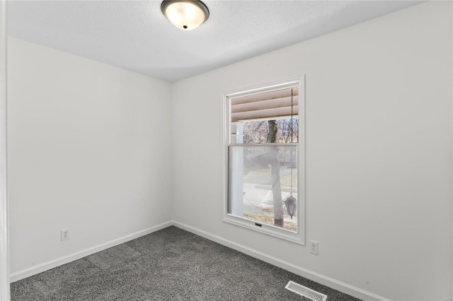 unfurnished room with visible vents, dark carpet, a textured ceiling, and baseboards