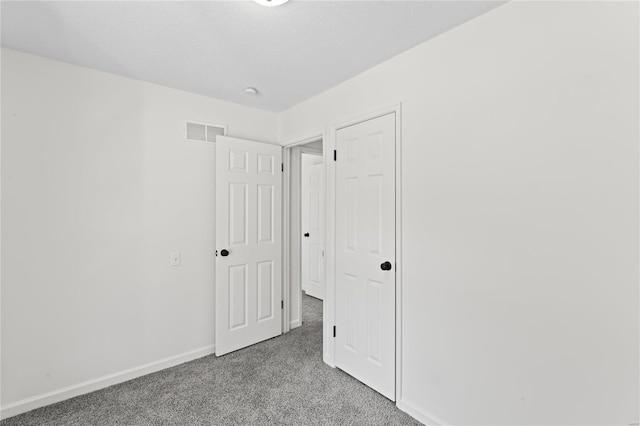 unfurnished bedroom featuring a textured ceiling, carpet floors, visible vents, and baseboards