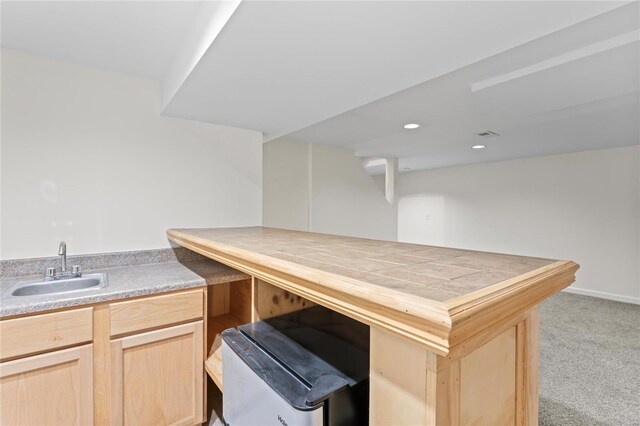 kitchen with recessed lighting, light colored carpet, light brown cabinetry, a sink, and a peninsula