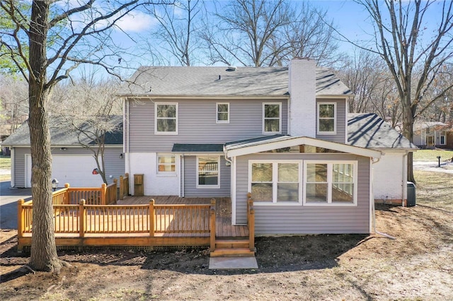 rear view of house featuring a garage, a chimney, a deck, and central AC unit