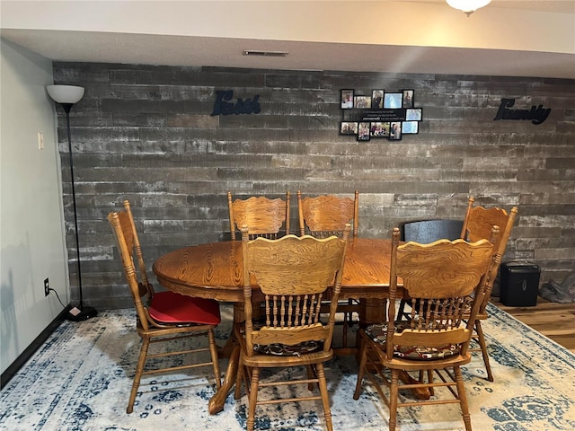 dining room featuring brick wall, visible vents, and baseboards