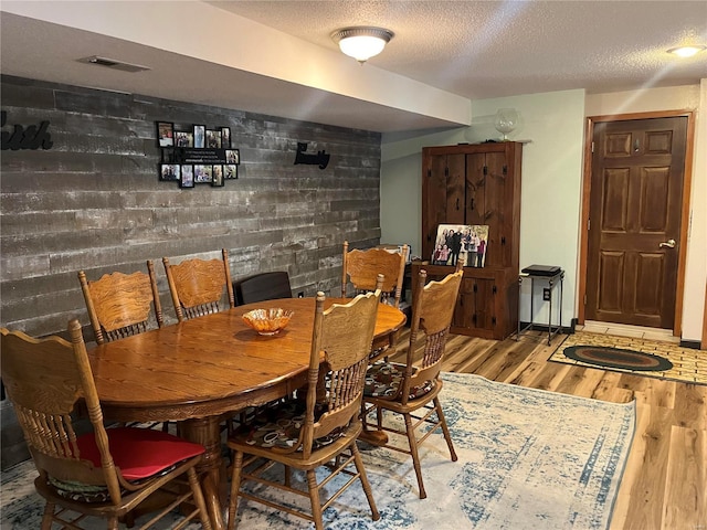 dining area with a textured ceiling, visible vents, and wood finished floors