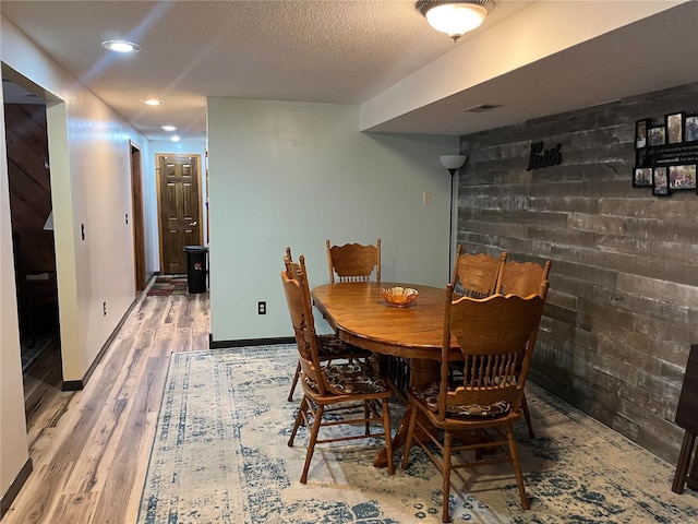 dining space featuring baseboards, visible vents, wood finished floors, a textured ceiling, and recessed lighting