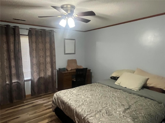 bedroom with visible vents, ceiling fan, wood finished floors, crown molding, and a textured ceiling