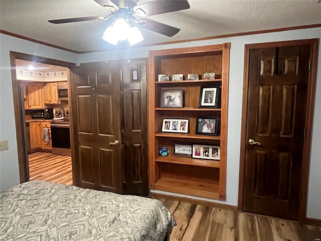 bedroom featuring a textured ceiling, ceiling fan, light wood-type flooring, and crown molding