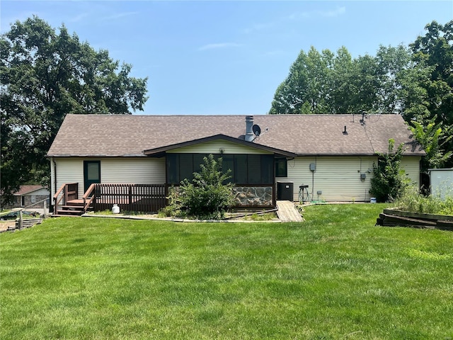 rear view of property with a sunroom, roof with shingles, and a yard