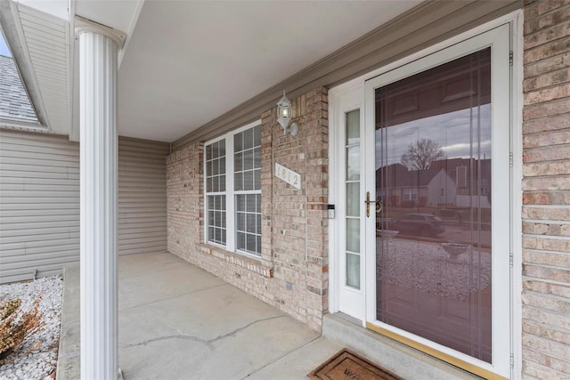 property entrance featuring a porch and brick siding