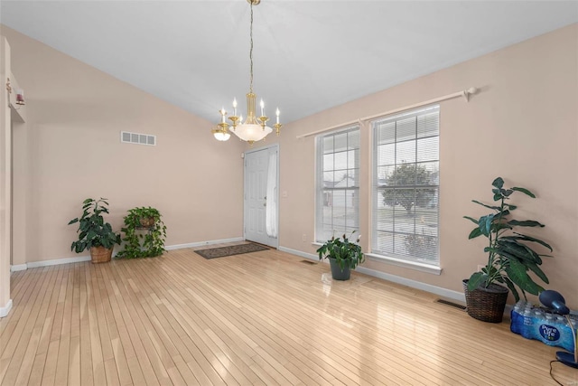 interior space with visible vents, vaulted ceiling, baseboards, and hardwood / wood-style flooring