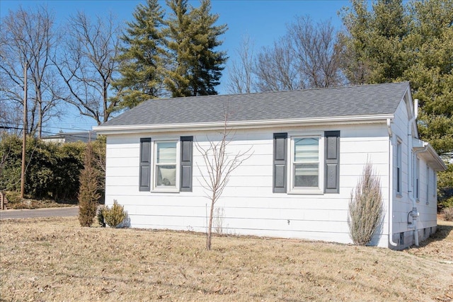 view of property exterior with a shingled roof and a lawn