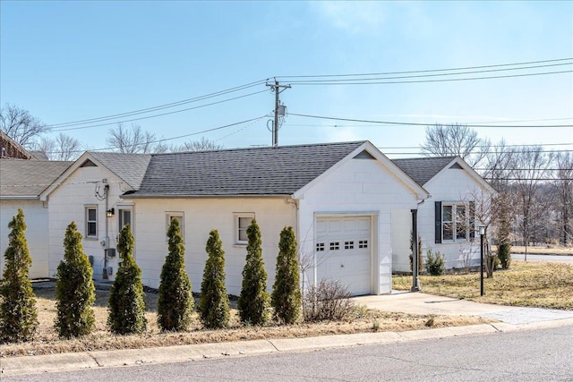 view of front facade featuring a garage, roof with shingles, and driveway